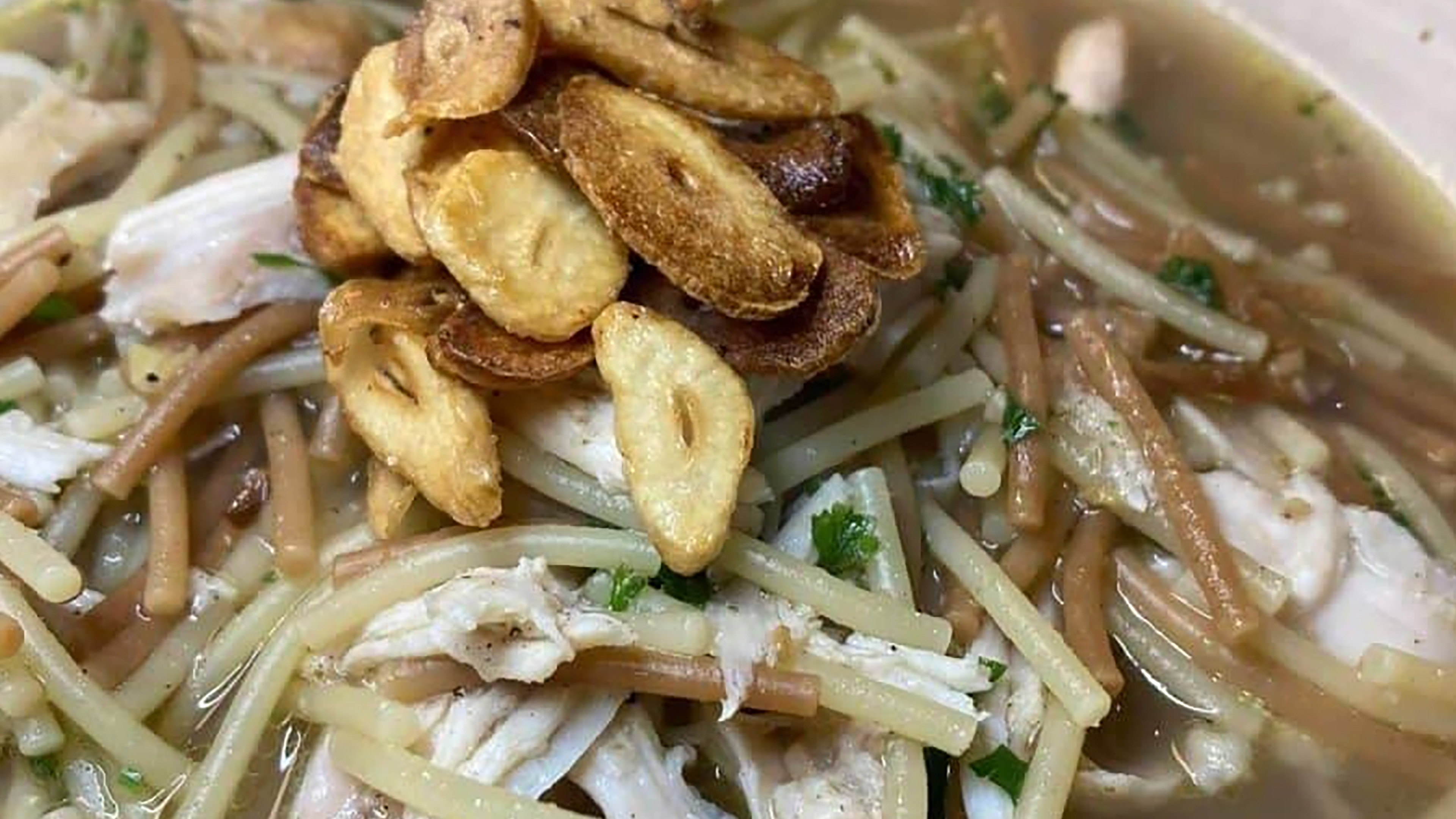 Warm Lebanese chicken noodle soup with thin noodles, chicken pieces, and crispy garnish.