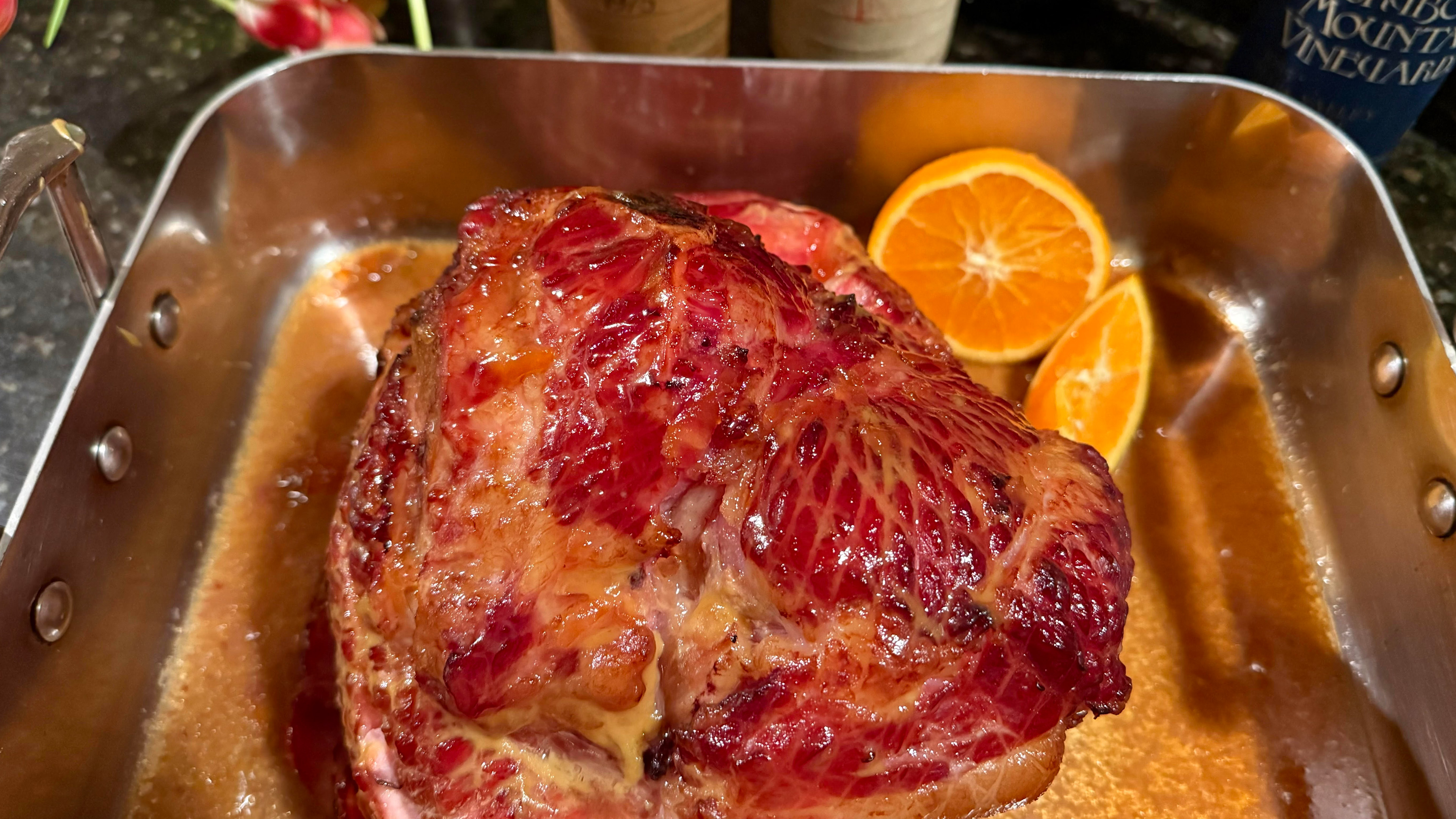 Header image of No-Recipe Sweet-Tart Glazed Ham in a roasting pan with orange pieces.