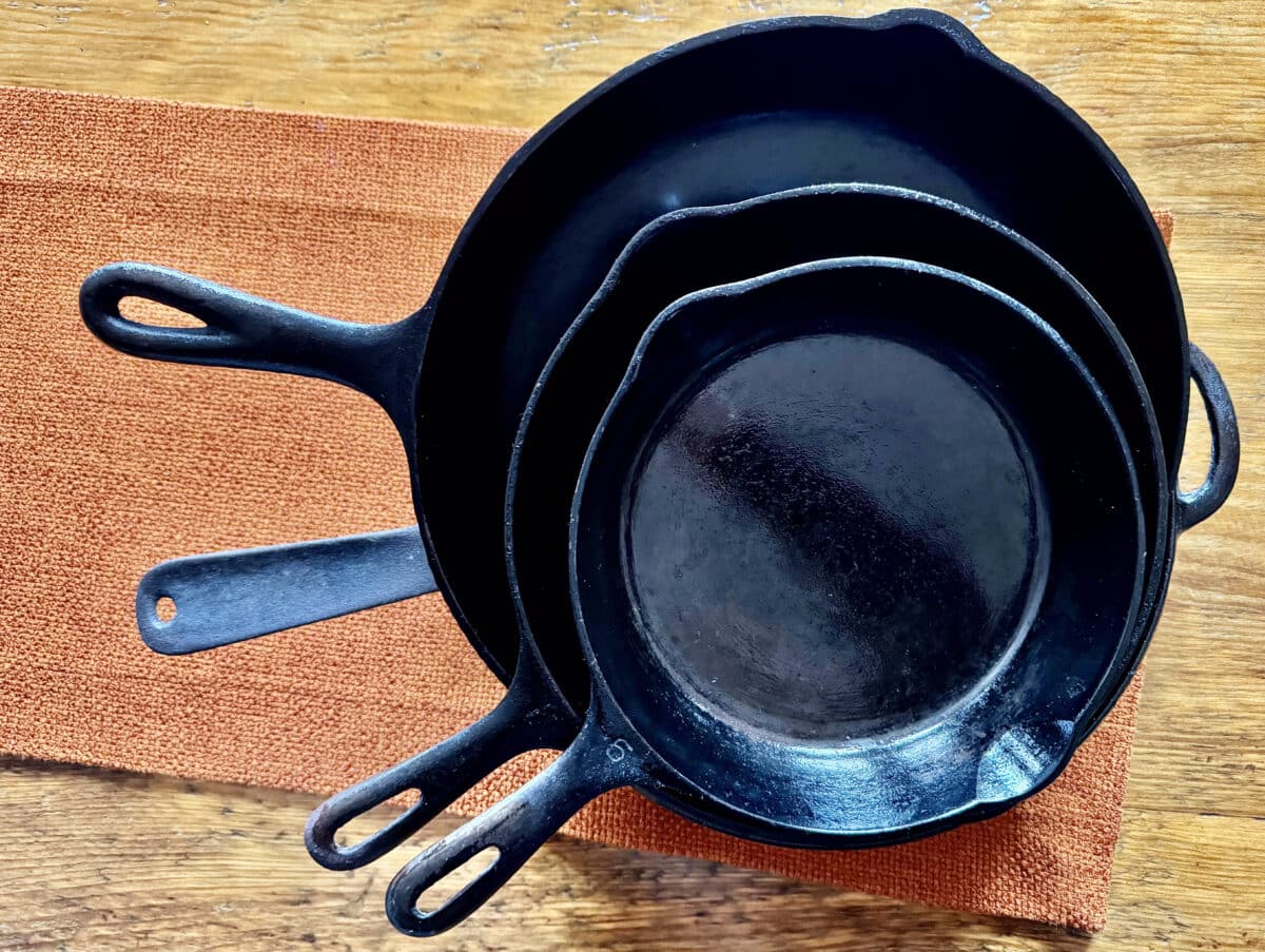 Four cast iron skillets in a pile