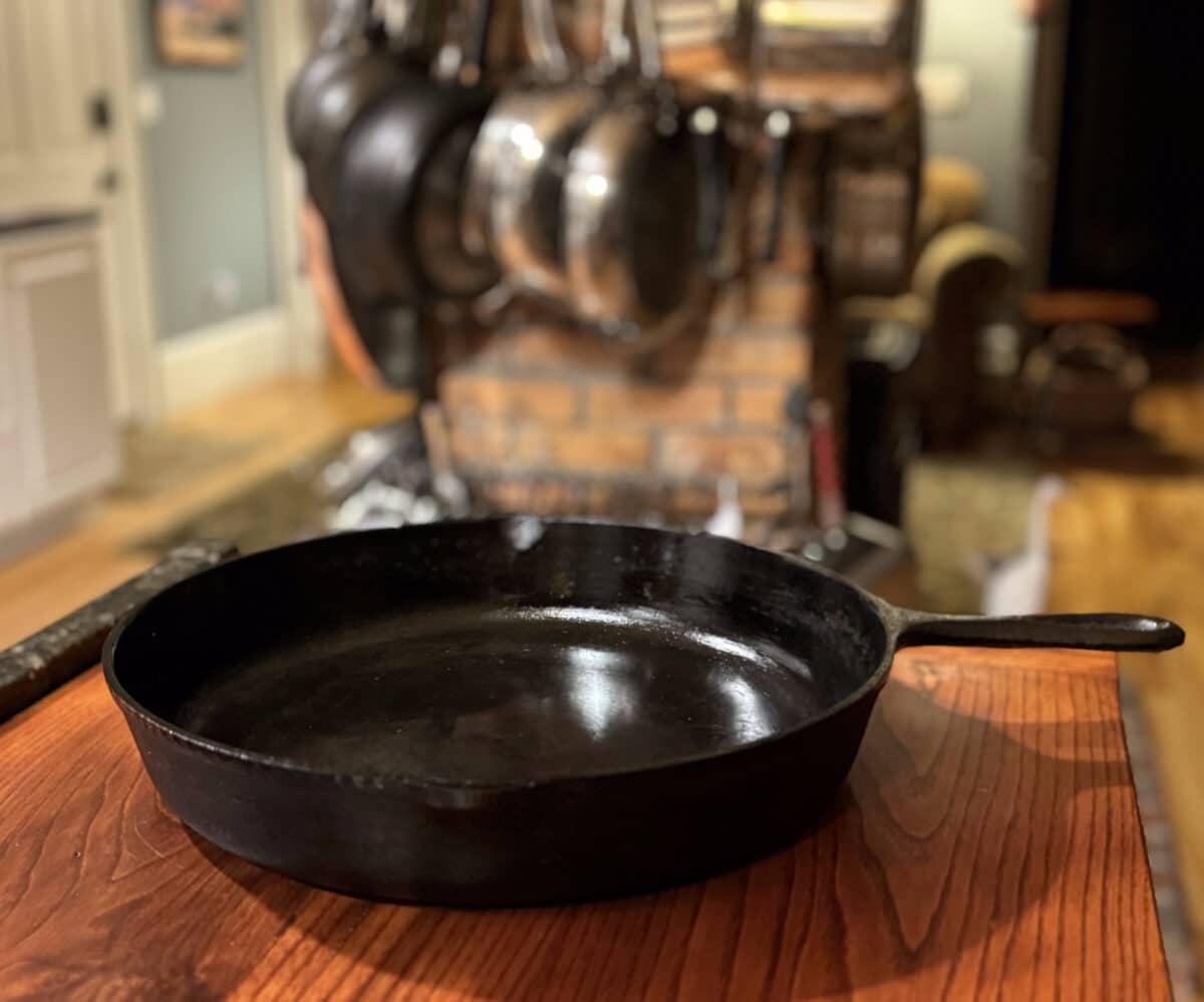 Cast iron skillet with pans hanging in background
