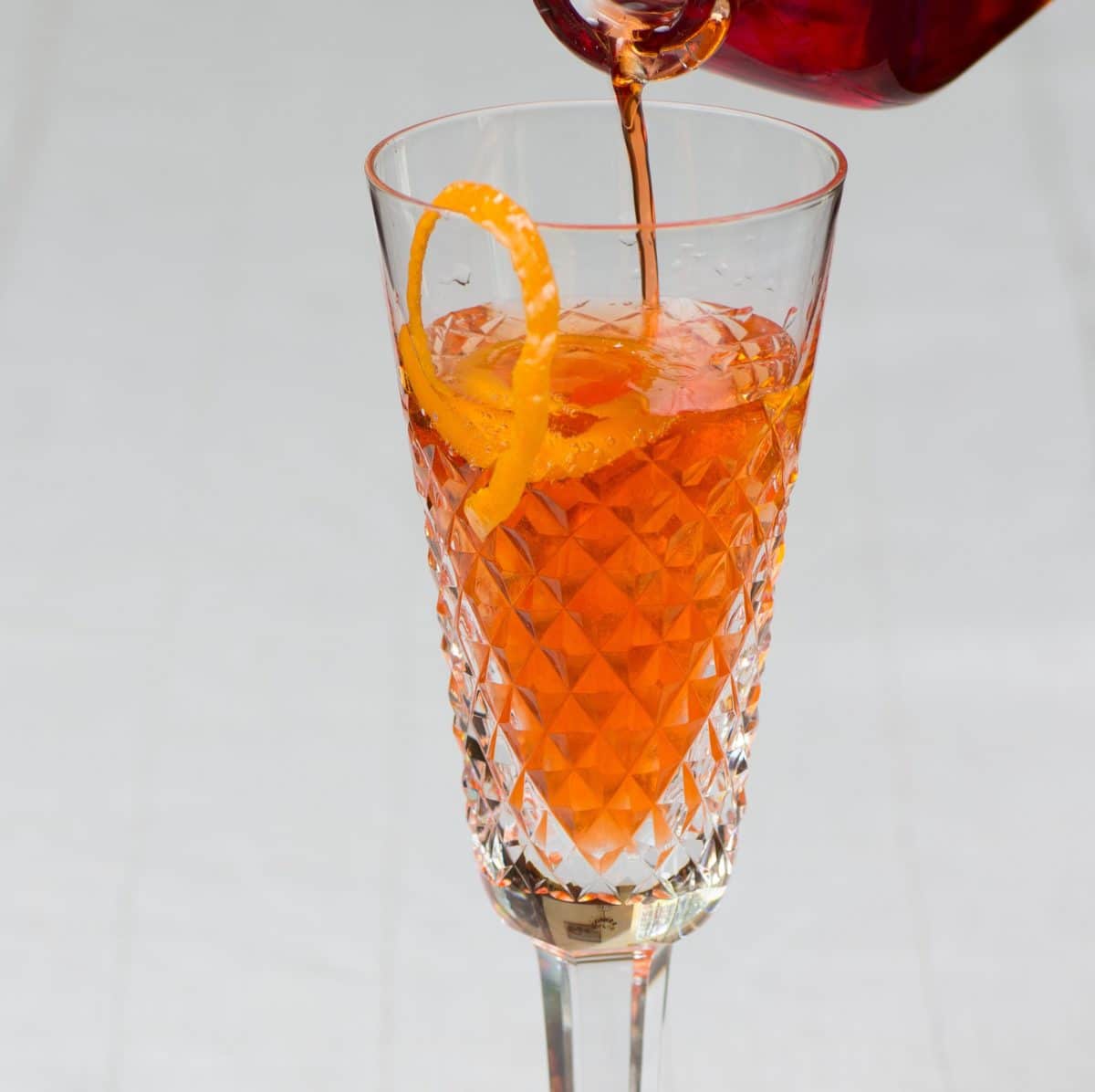 Pouring an Amara Champagne Cocktail with an orange twist.
