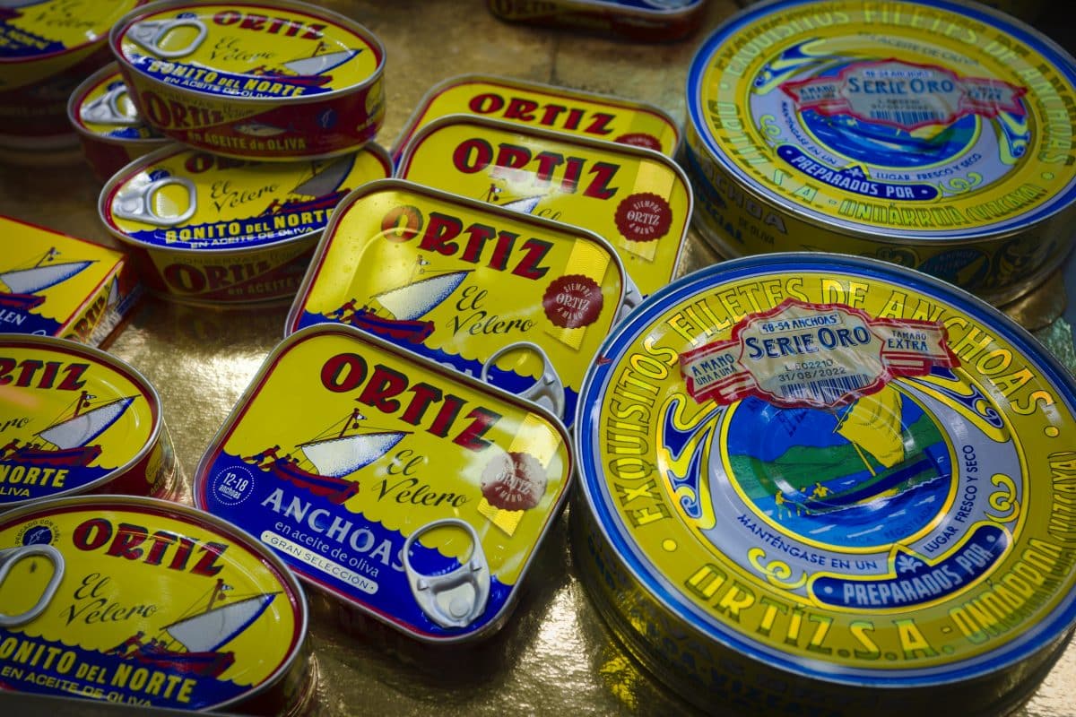 Tins of Ortiz anchovies displayed with vivid branding.