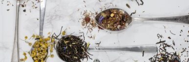Variety of tea leaves displayed on a white surface