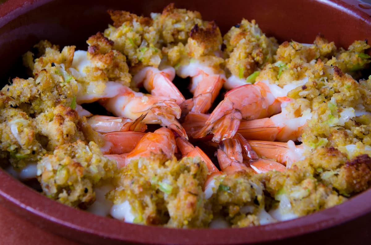 Clay dish with baked shrimp topped with crumbs