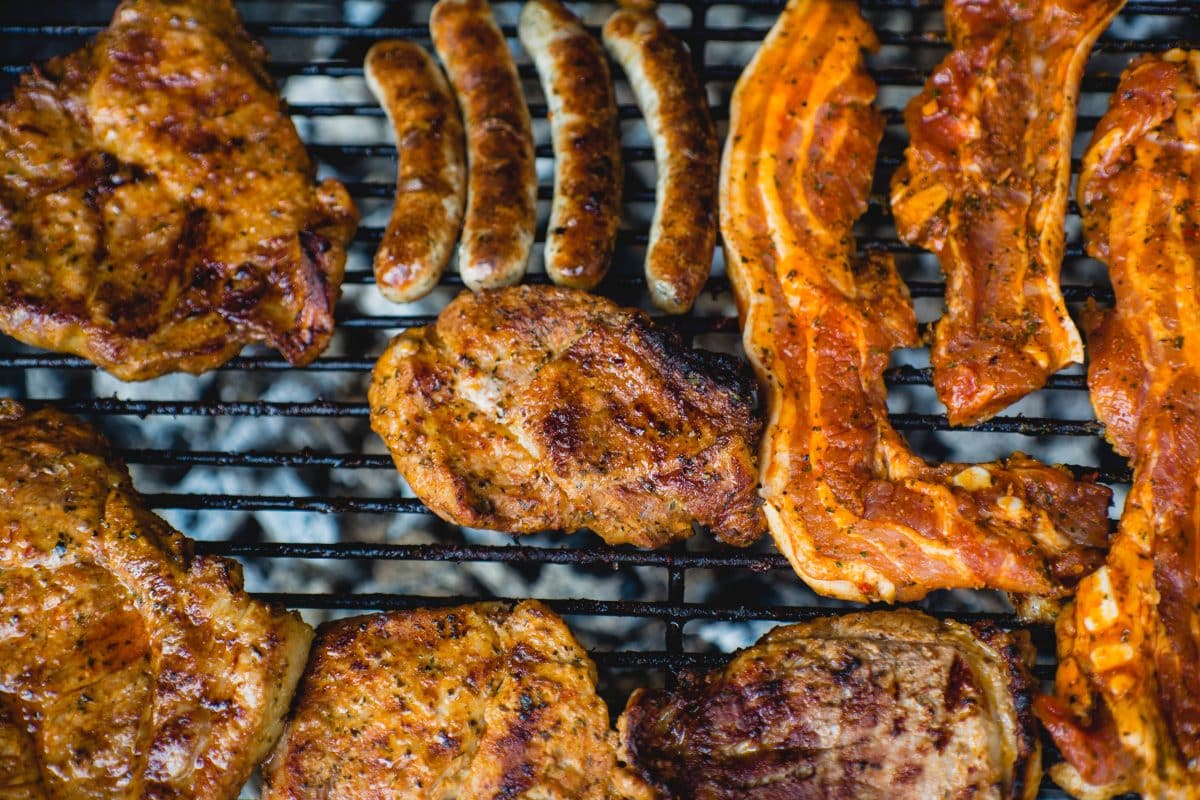 Grilled sausages, pork ribs, and meat cuts on a barbecue grill