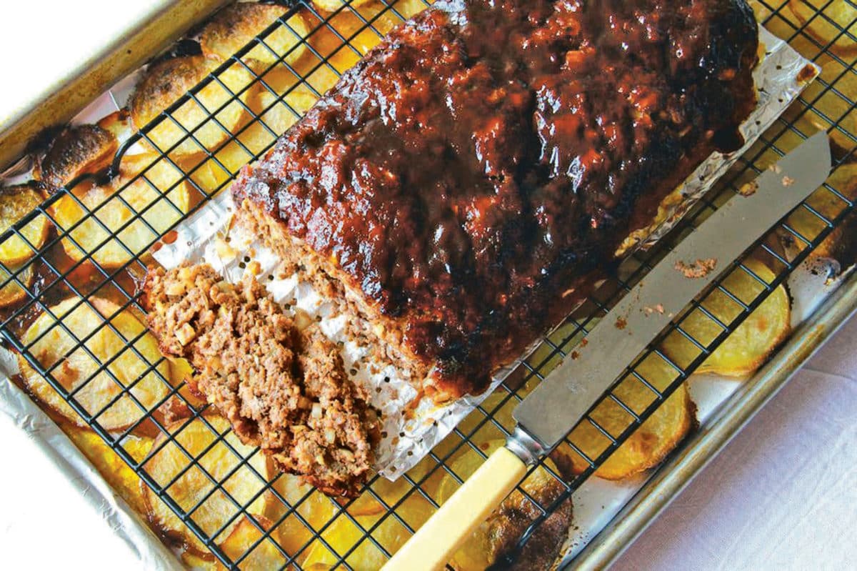 Close-up of a barbecue meatloaf served with potatoes on a sheet pan.