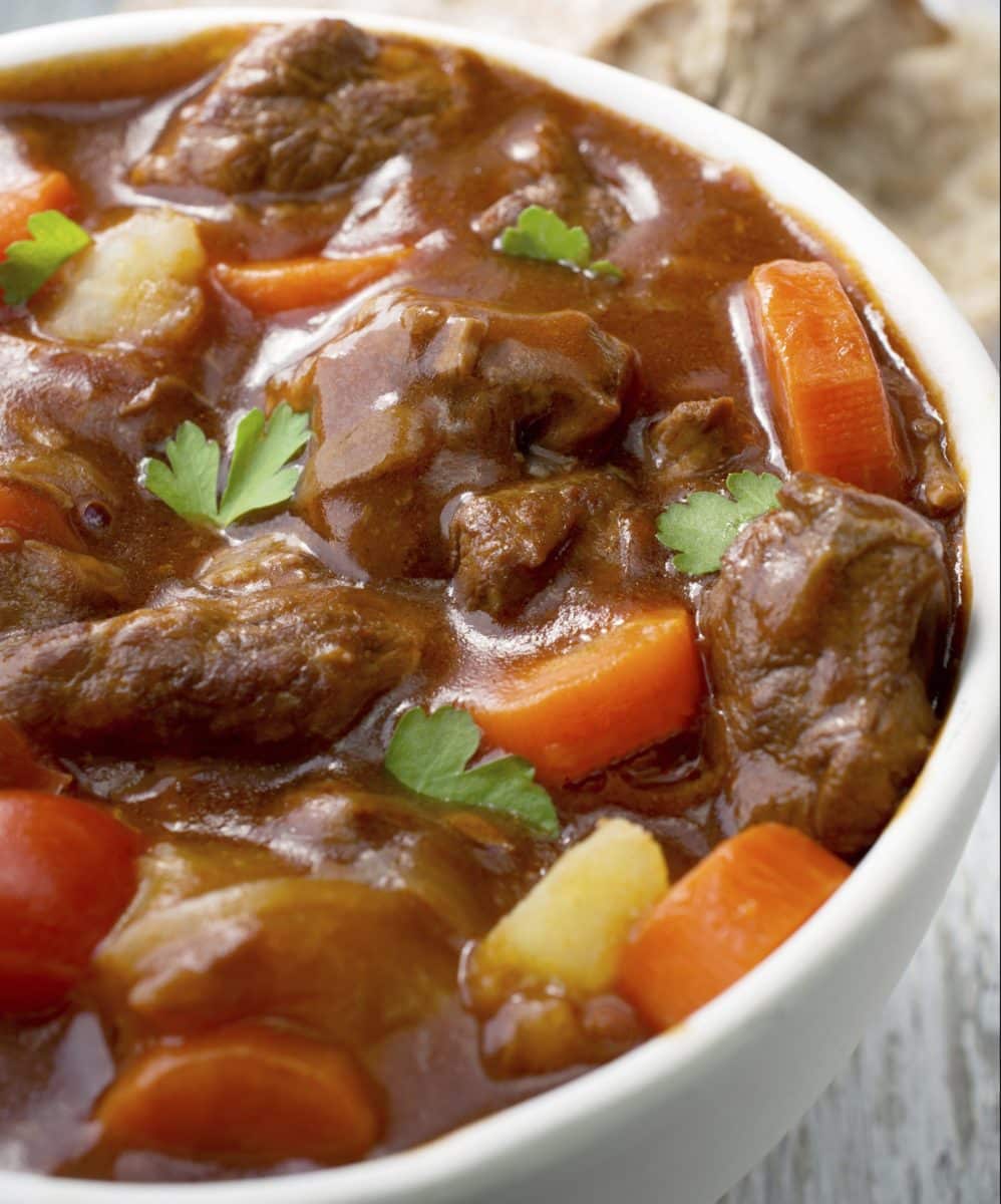 Hearty beef stew in a white bowl with vegetables