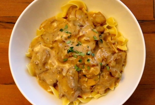 Close-up of a bowl of beef stroganoff topped with parsley.