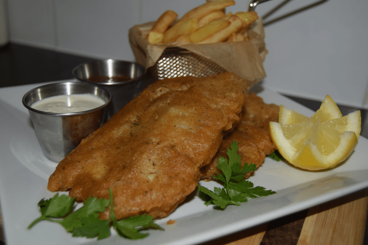 Golden beer-battered fish with fries, lemon, and dip