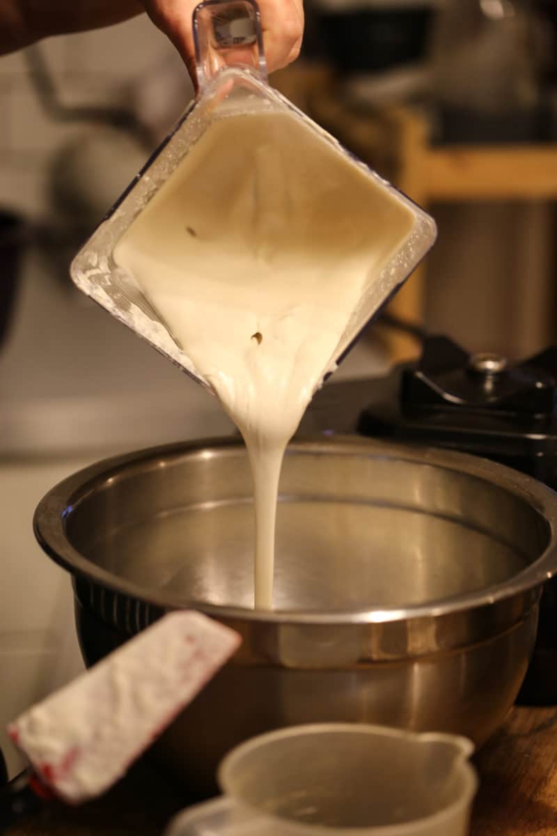 Texture of blended cashew, being poured from a blender, for making queso fresco