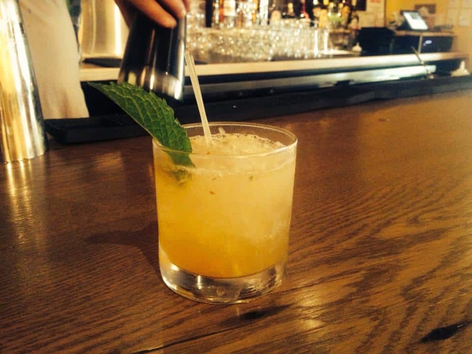 Bourbon Peach Smash cocktail garnished with a mint leaf