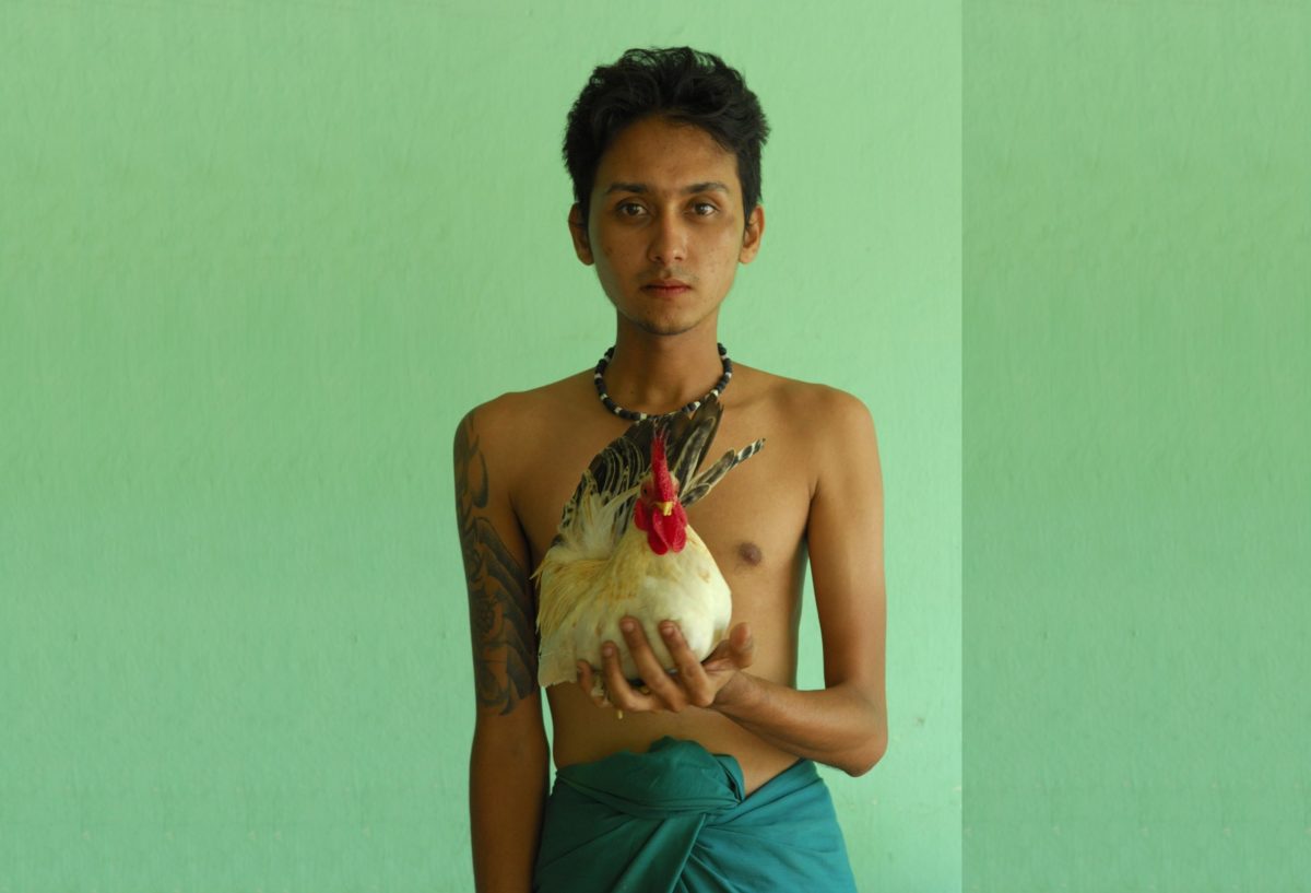 Young boy holding a pet chicken in Mandalay, Myanmar.