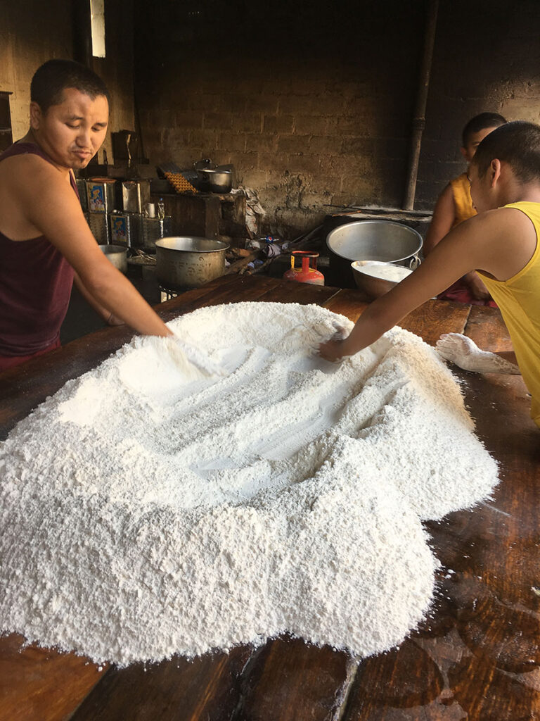 Two boys working together on a large pile of flour
