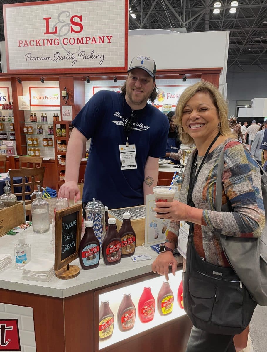 Two individuals at the Brooklyn Seltzer booth with products displayed.