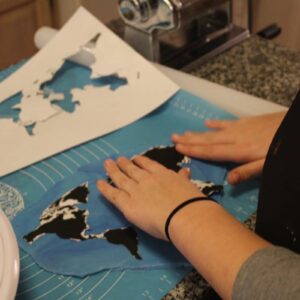 Hands placing world map design on cake
