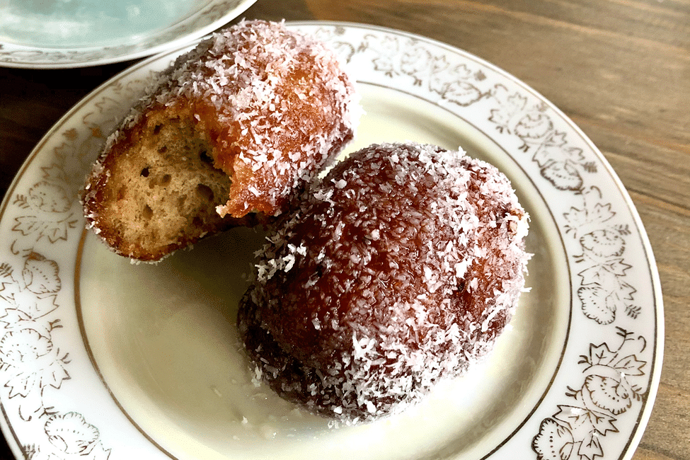 Close-up view of coconut-coated Koesisters with a bite taken out.