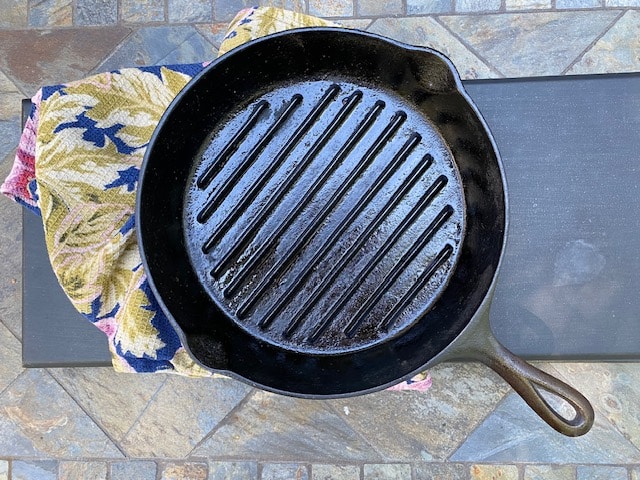 A cast iron skillet with ridges on a table with a floral cloth underneath.