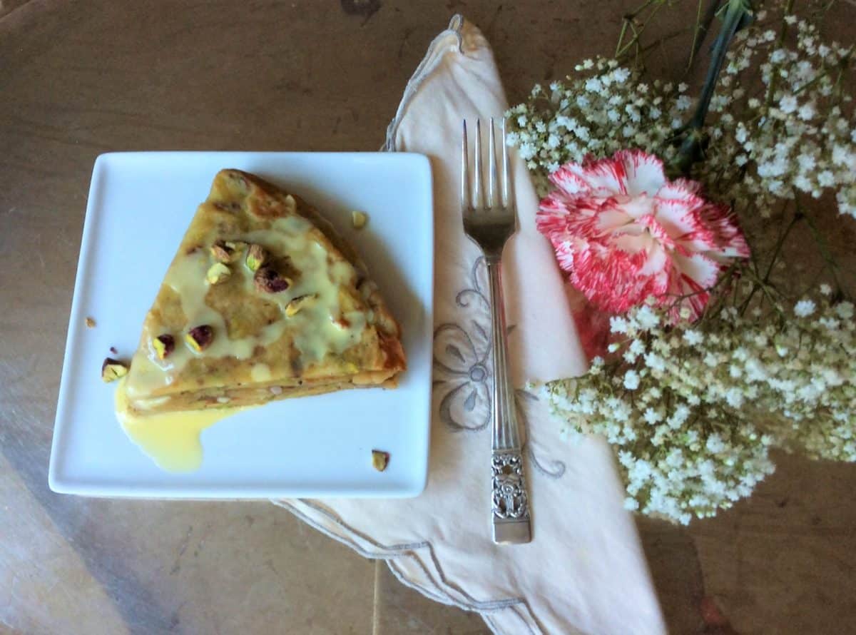 Delicious Parsi sweet pancake on a plate drizzled with syrup and garnished.