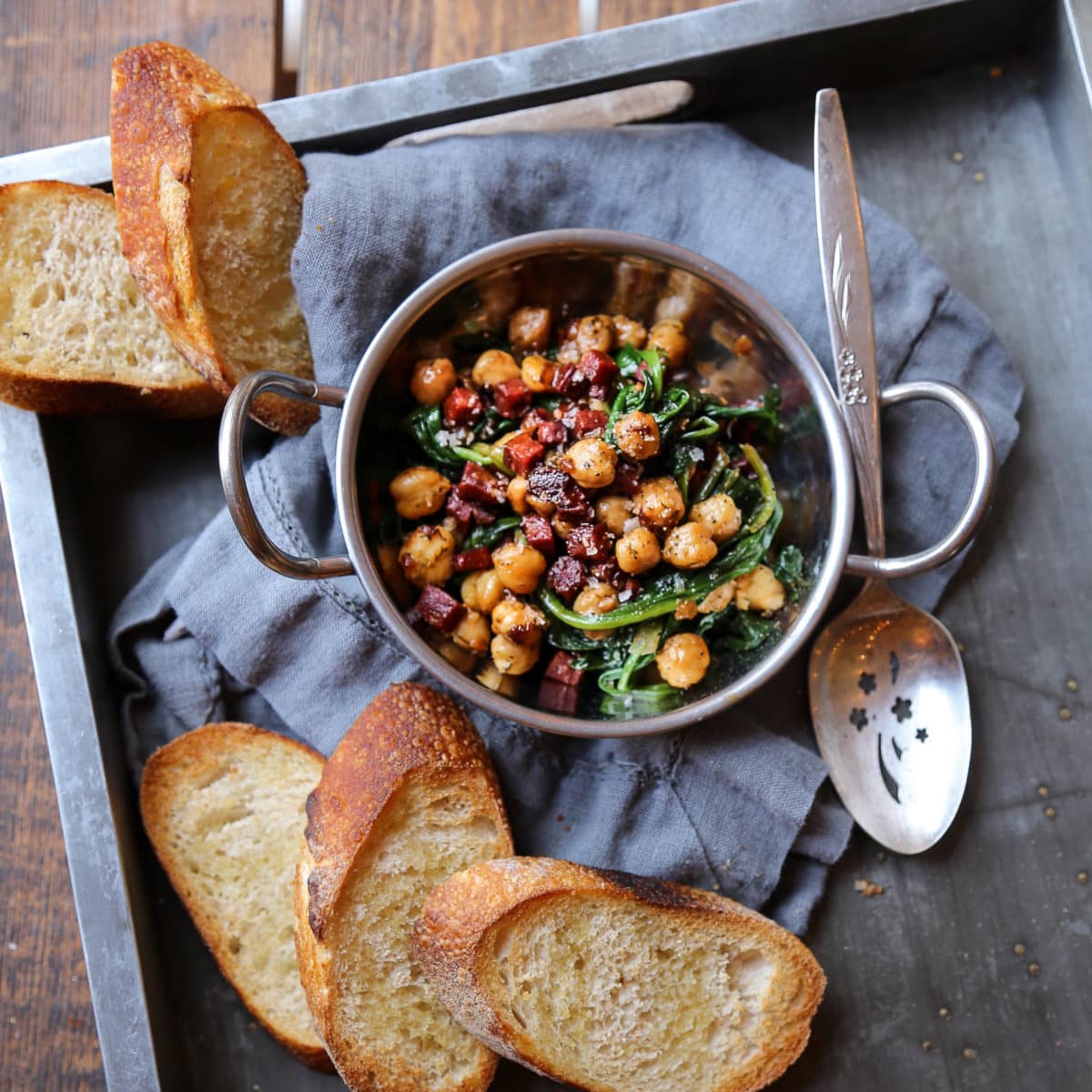 An open faced sandwich with chickpeas, spinach, and chorizo.