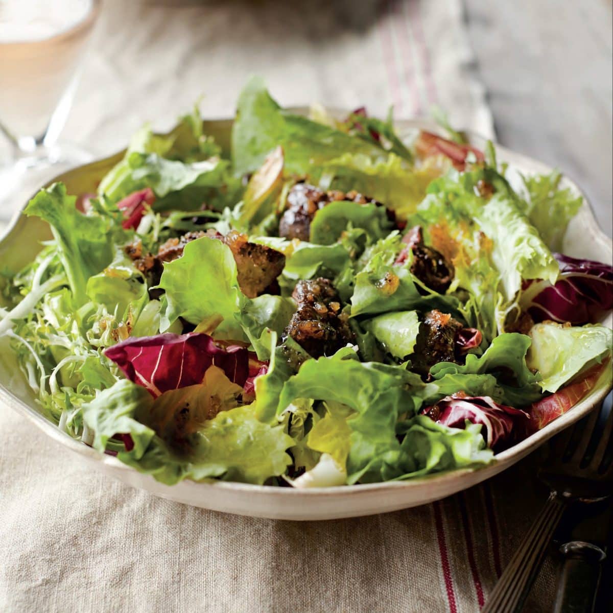 Bowl of chicory salad with sautéed chicken livers on a lined cloth