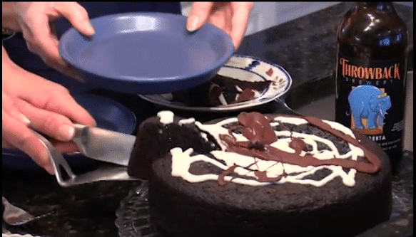 Slice of chocolate beer batter cake being served with a beer bottle in the background.