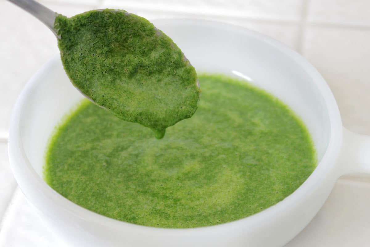Fresh cilantro-mint chutney dripping from a spoon into a white bowl.