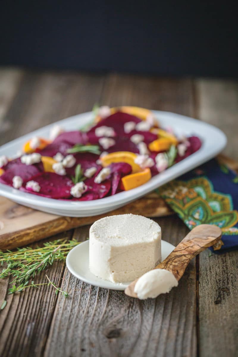 A vibrant dish of citrus herb roasted beets topped with vegan macadamia ricotta.