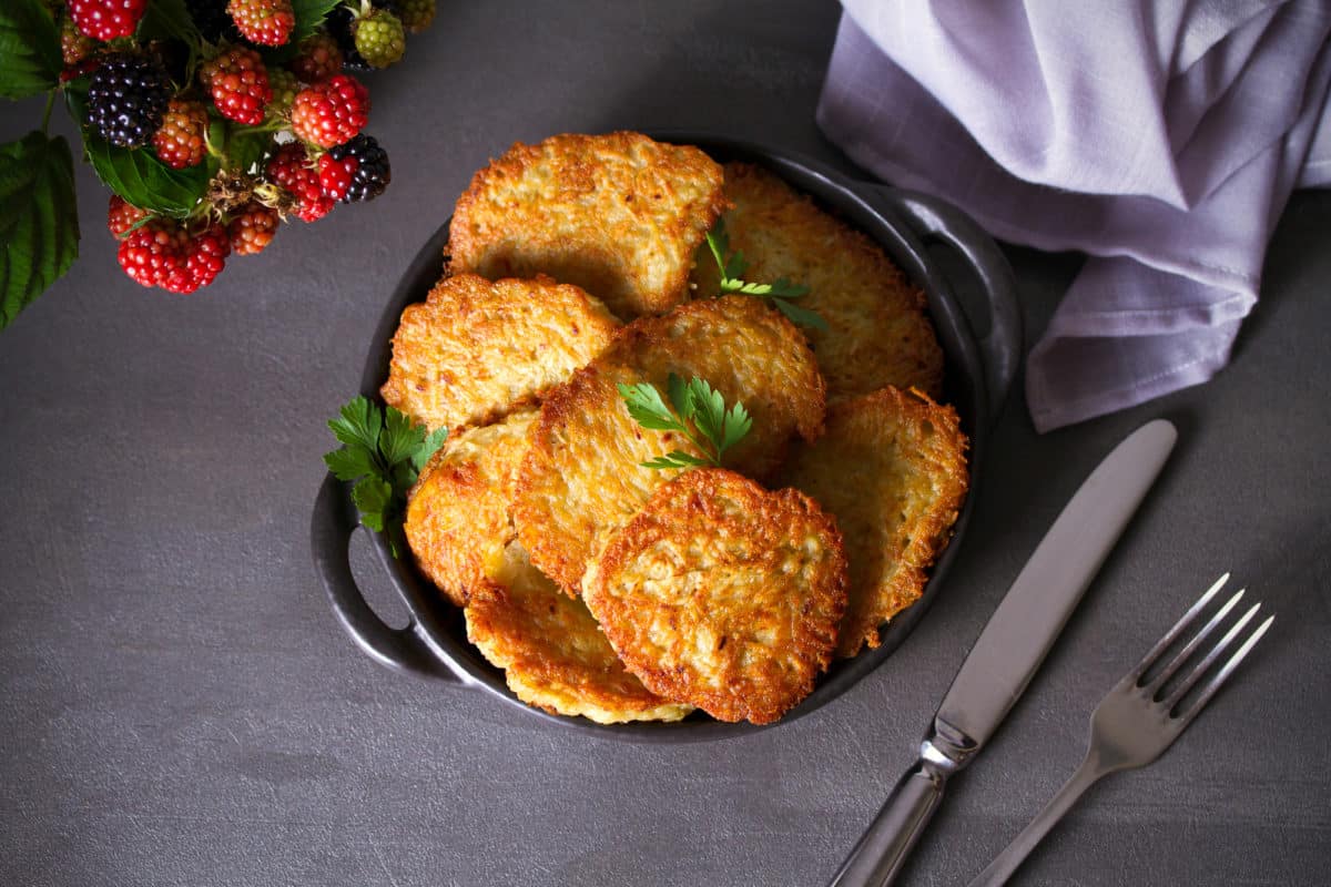 A plate of golden brown potato latkes garnished with parsley