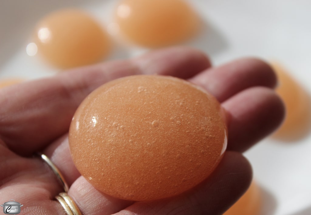 Detailed view of a transparent edible bubble held between fingers.