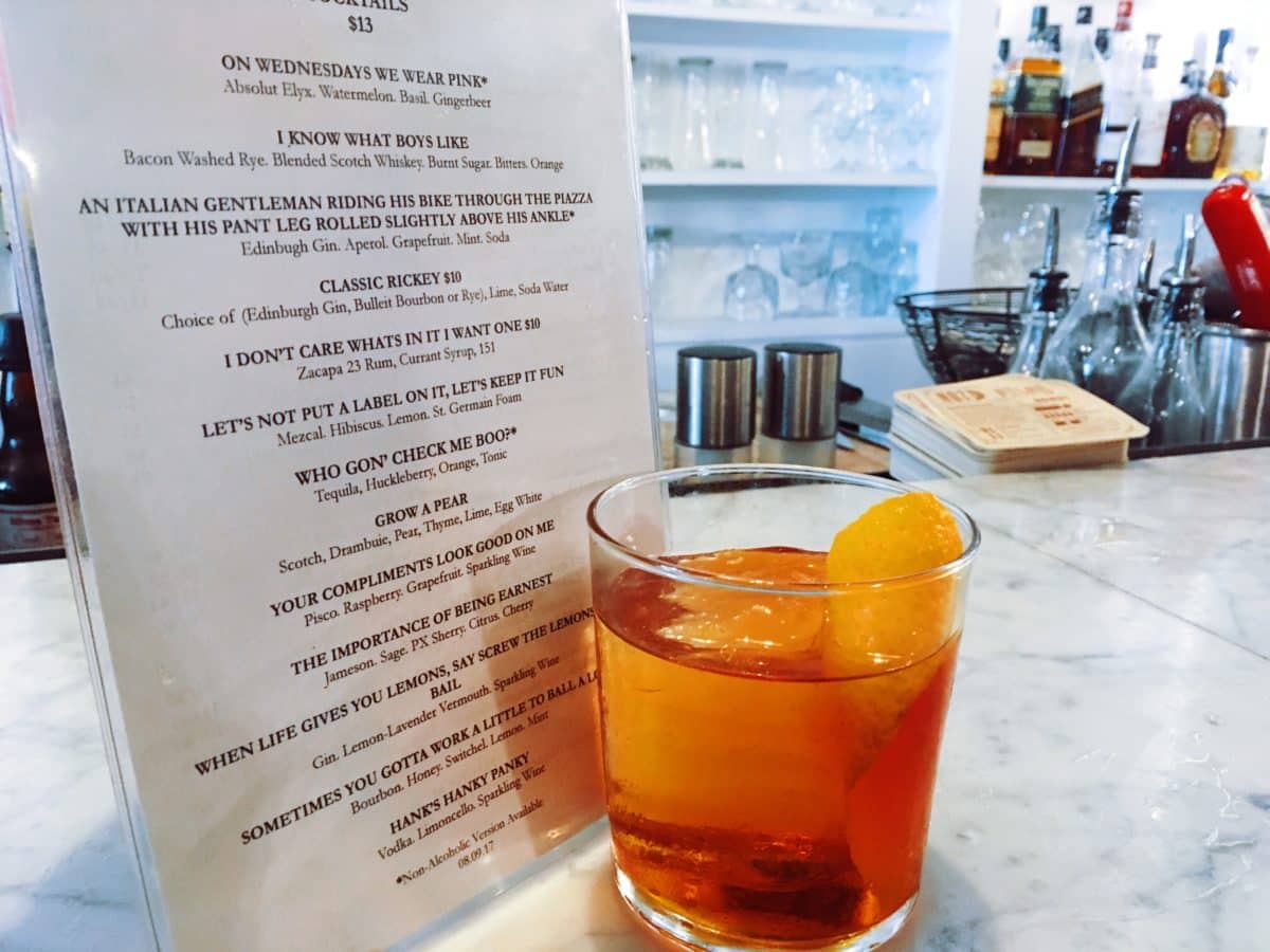 A drink menu and a drink in an Old Fashioned glass