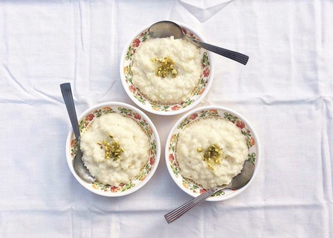 A top-down view of three bowls of Coconut & Jaggery Kheer (Rice Pudding) garnished with jaggery.