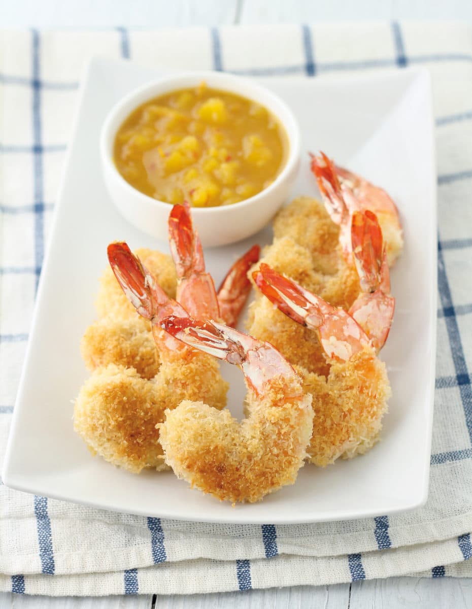 Close-up of coconut shrimp served with a tangy dipping sauce.