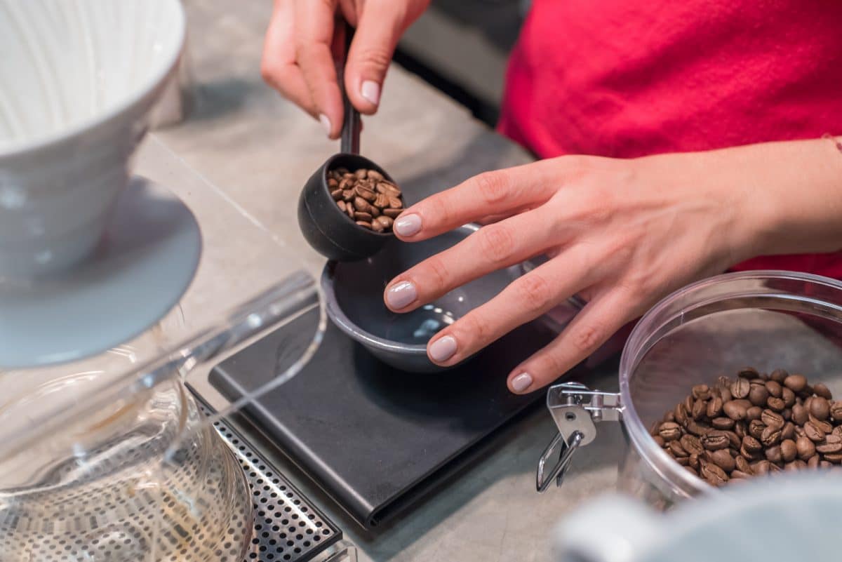 Hand pouring coffee beans on a digital scale