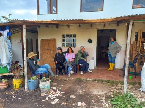 People relaxing outside a house after a hike with a cup of tinto.