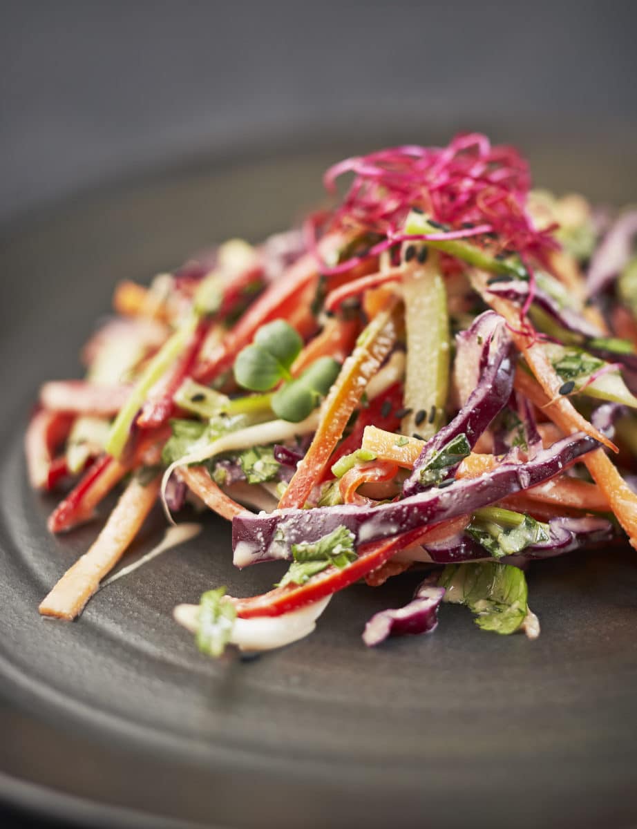 Colorful turnip slaw salad on a dark plate.