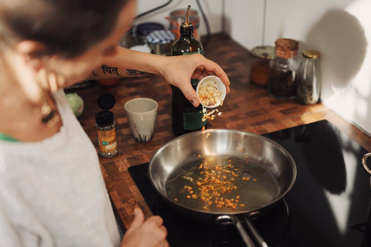 Person adding ingredients to a heated pan