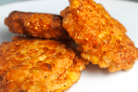 Golden corn fritters on a white plate.