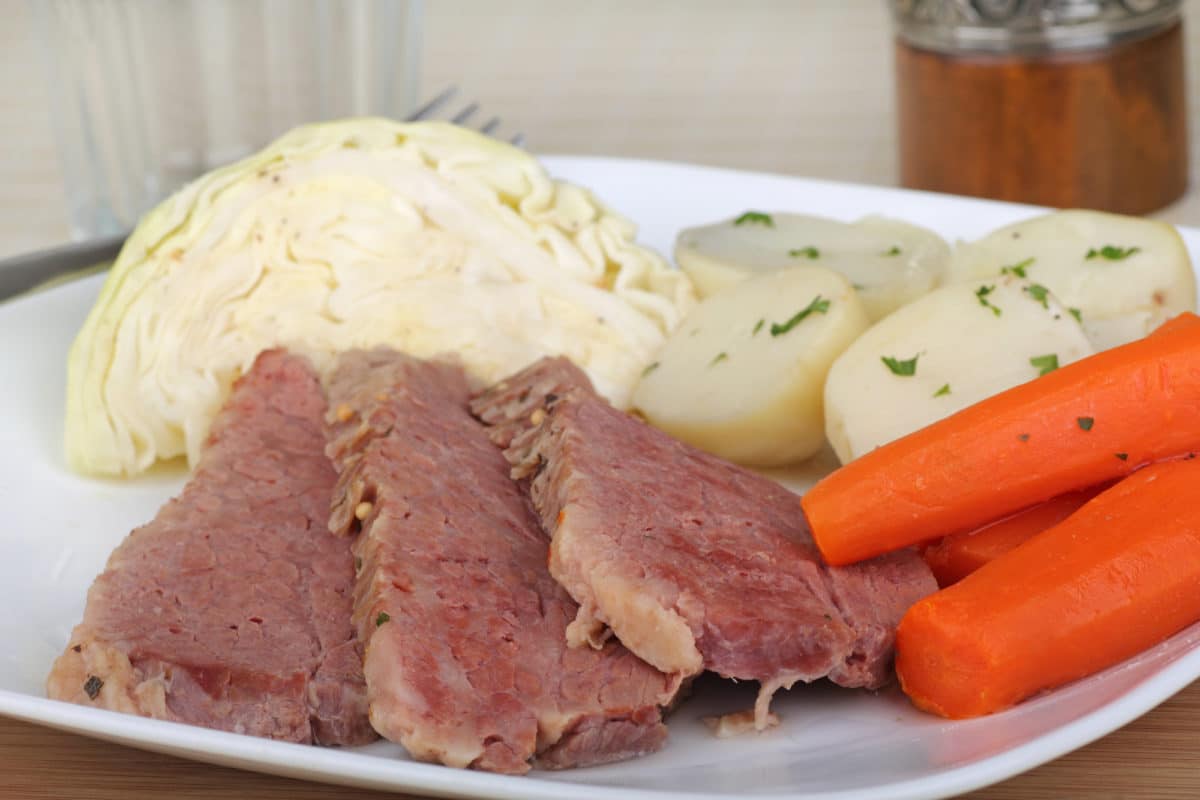 Corned beef slices with mashed potatoes, carrots, and boiled potatoes.
