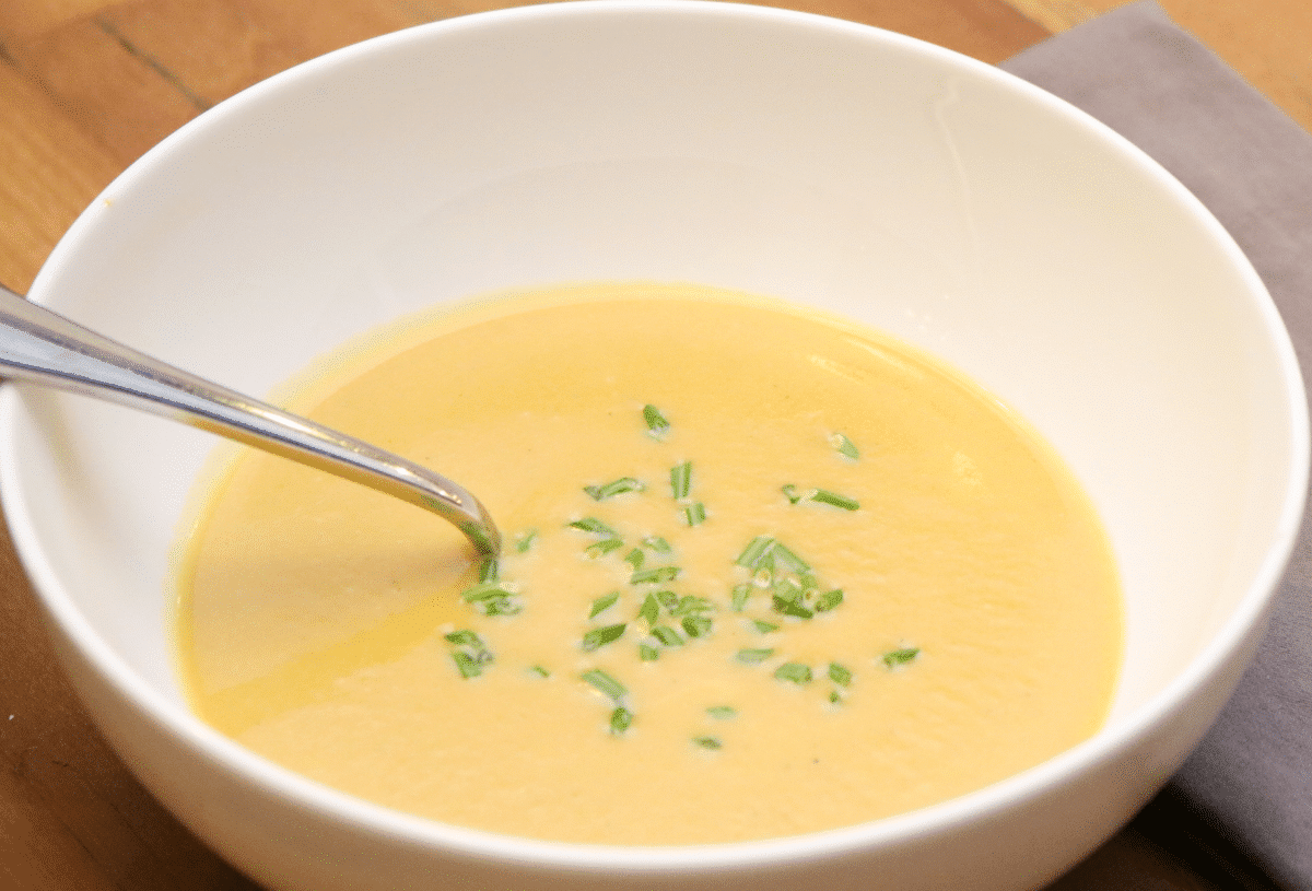 A bowl of creamy potato leek soup garnished with chopped green onions.