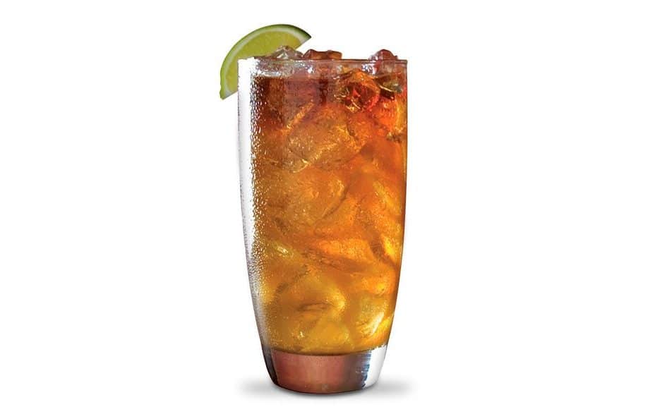 A tall glass filled with the Dark and Stormy cocktail with a lime garnish.