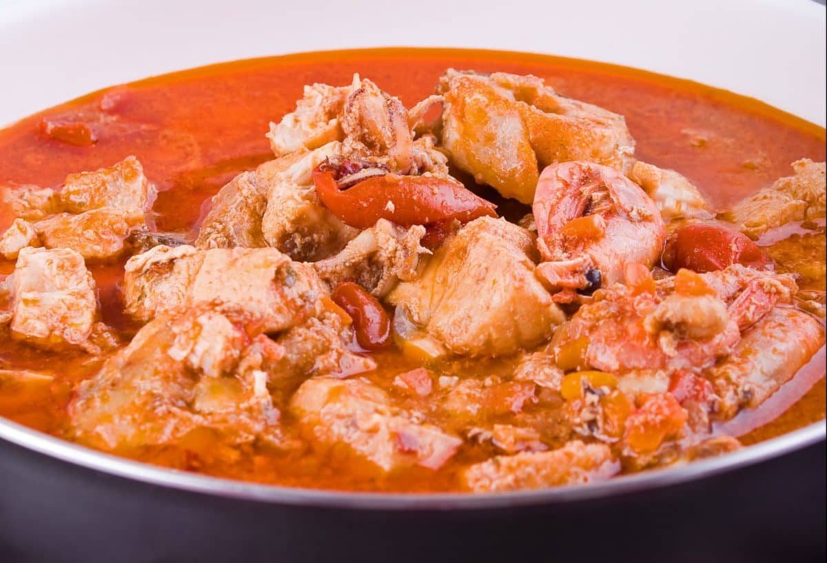 Close-up of a bowl filled with fish stew containing various seafood and vegetables.