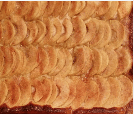 Freshly baked apple kuchen with neatly arranged apple slices.