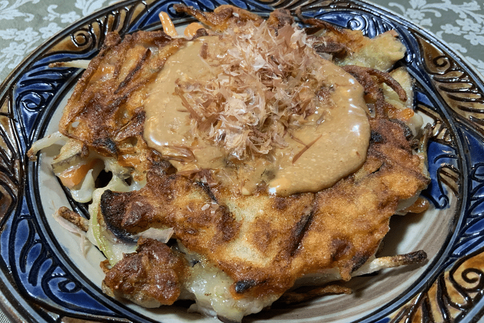 A mouth-watering Okonomiyaki with sauce and toppings.
