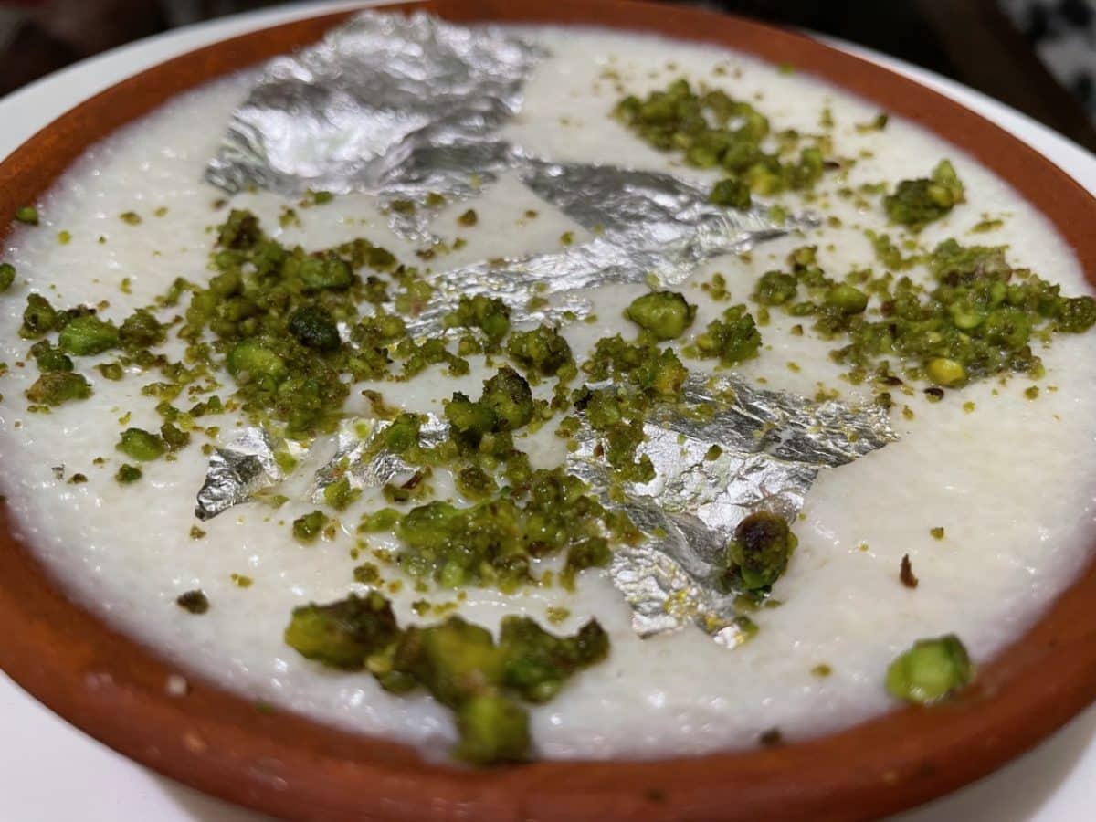 A bowl of Phirni, a traditional Indian rice pudding, garnished on top.