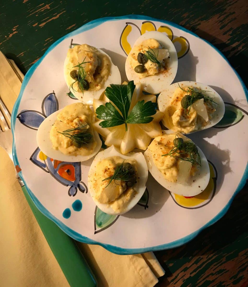 Plate of deviled eggs with crab, garnished with capers and dill