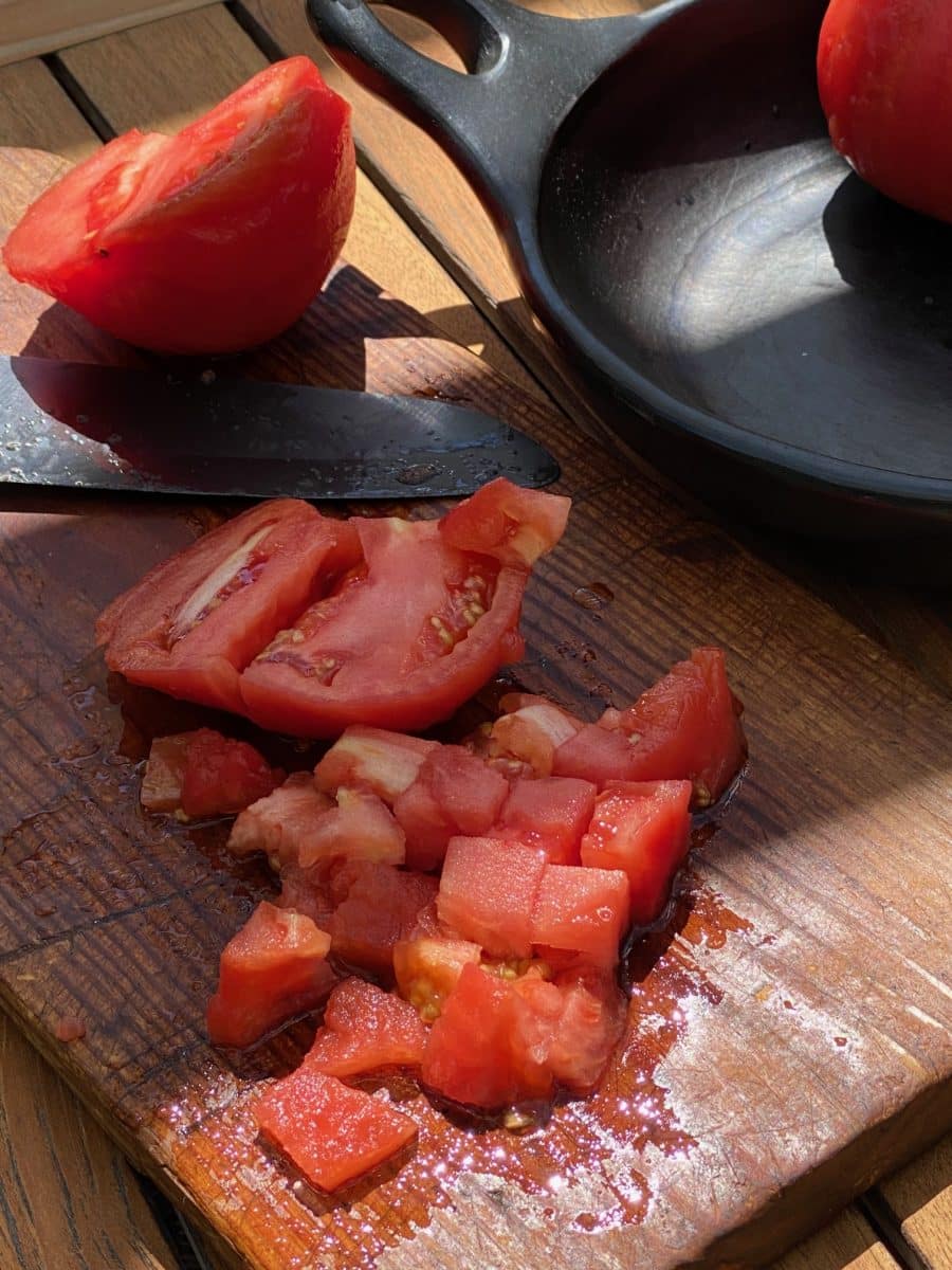 Fresh diced tomatoes on a wooden cutting board.