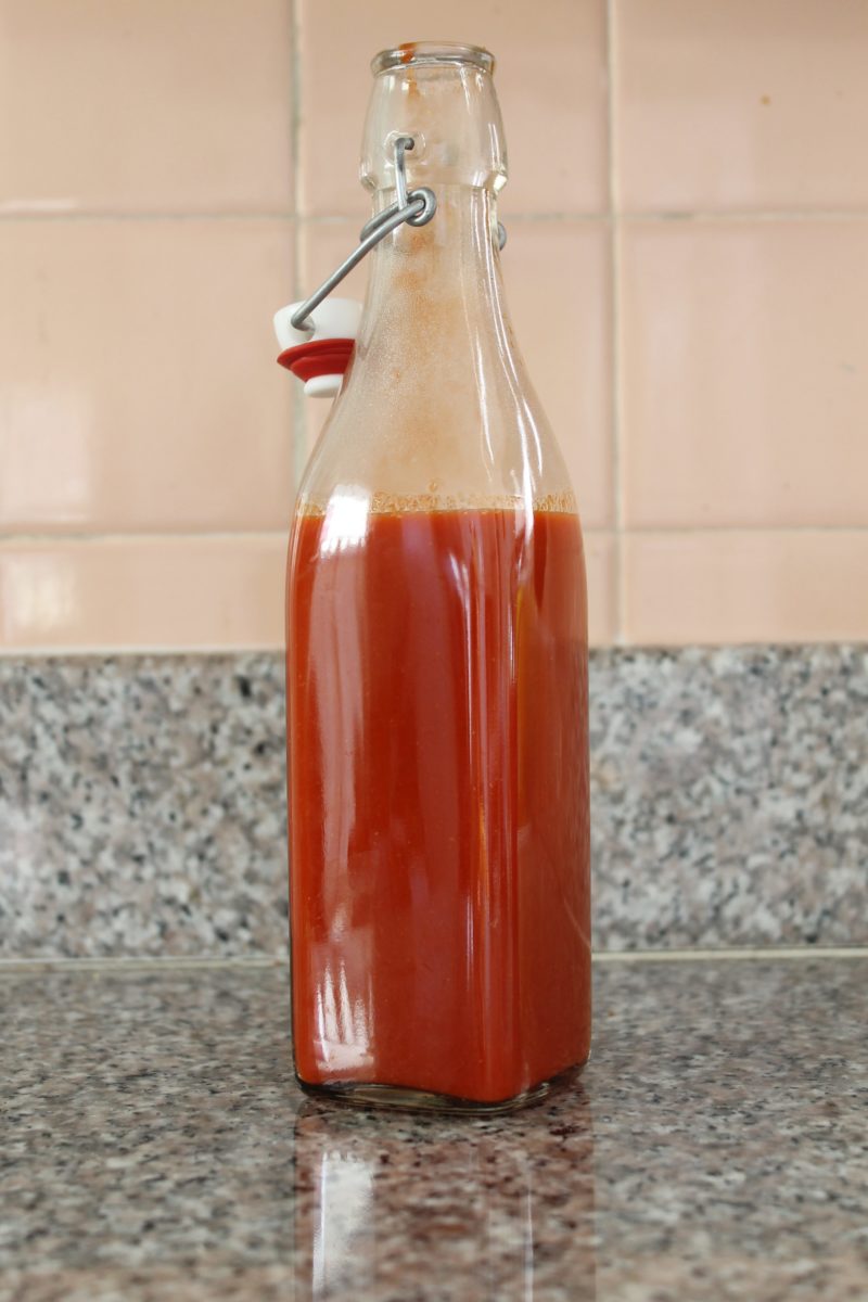 A sealed glass bottle filled with homemade sriracha.