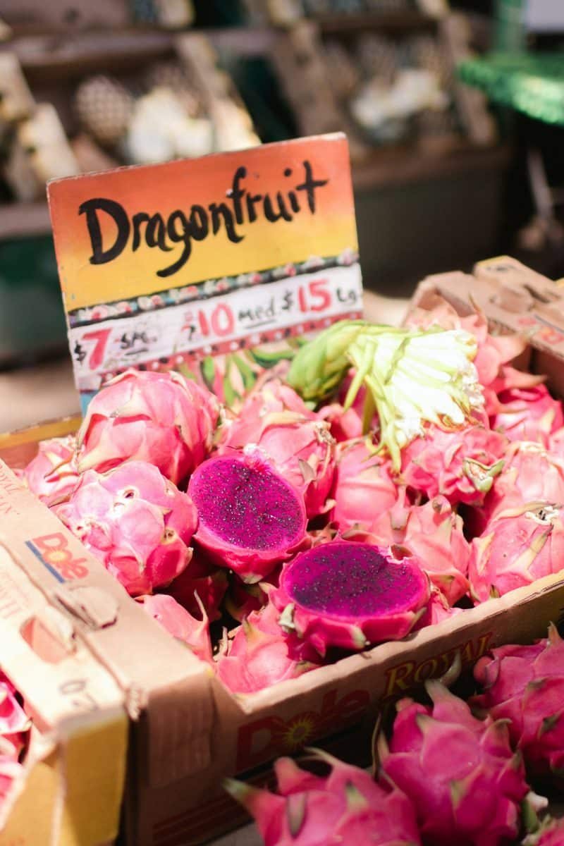Dragonfruits with a vibrant purple interior displayed in a market.