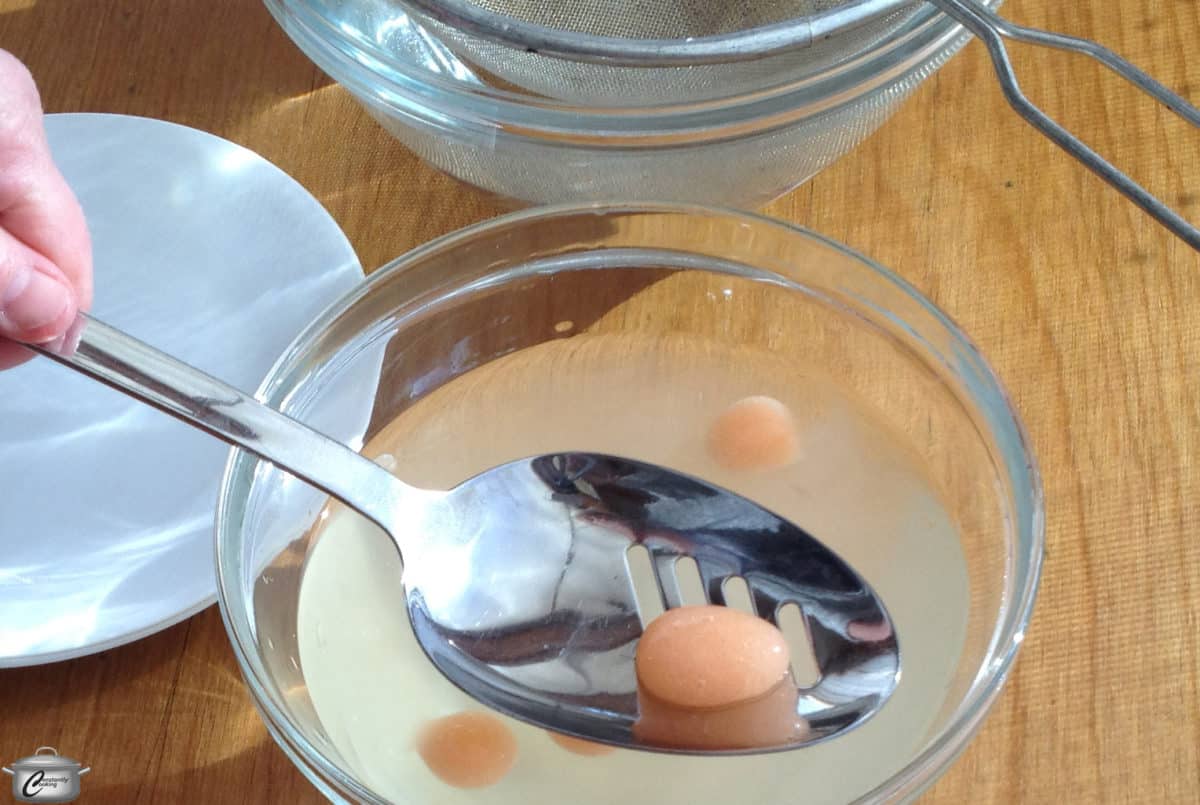 Dropping an edible bubble into a mixture using a spoon.