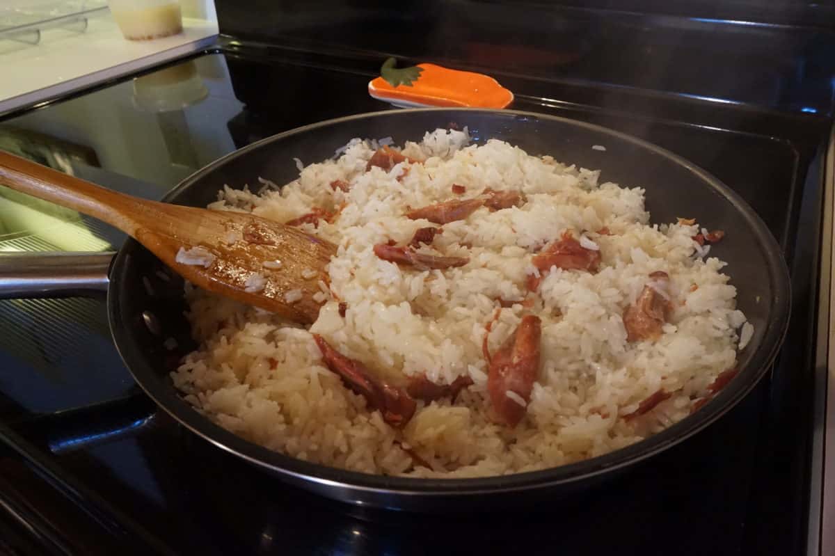 Rice cooking in a pot with duck confit pieces.
